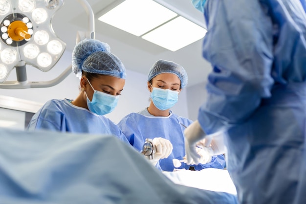 Multiethnic healthcare workers performing surgery on patient at operation theater Medical colleagues operating in emergency room at hospital They are in scrubs