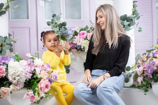 Multiethnic mom and daughter are sitting on the porch of the house