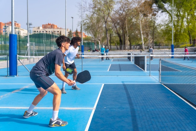 Multiethnic pickleball team playing with friends in an outdoor court