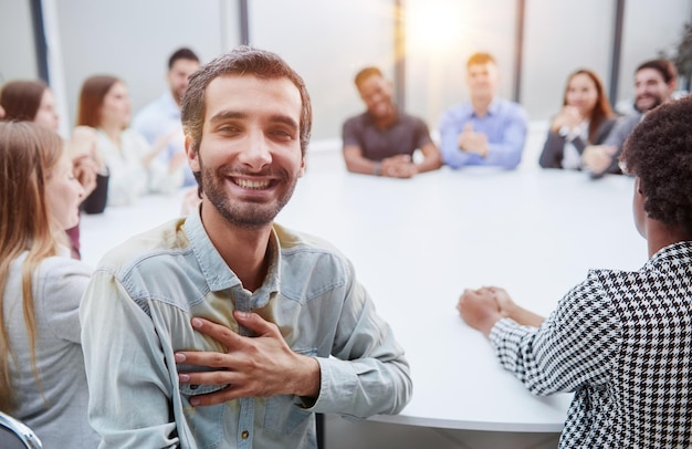 Multiethnic smiling people sitting at desk and looking at camera