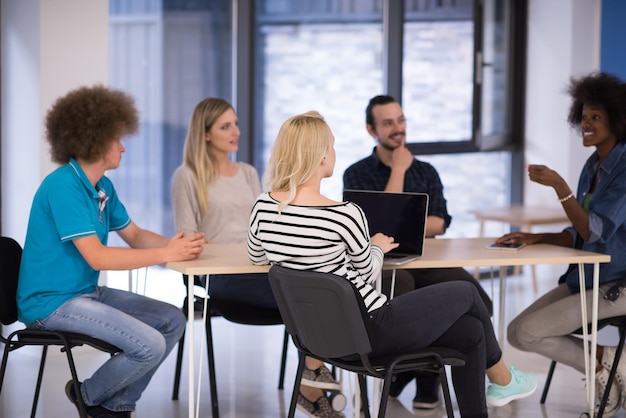 Multiethnic startup business team on meeting in modern bright office interior brainstorming, working on laptop and tablet computer