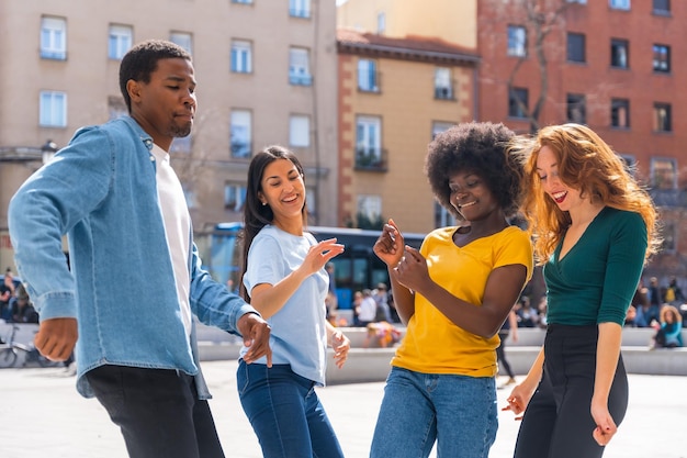 Multiethnic young friends dancing a city square group of happy people having fun together