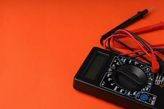 Multimeter on orange background space for text