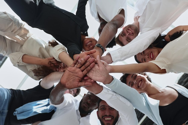 Multinational business team looking down putting hands together