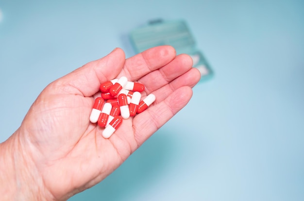 Multiple colours pills in senior hand on blue background. Taking Your Medication. Medicine concept.