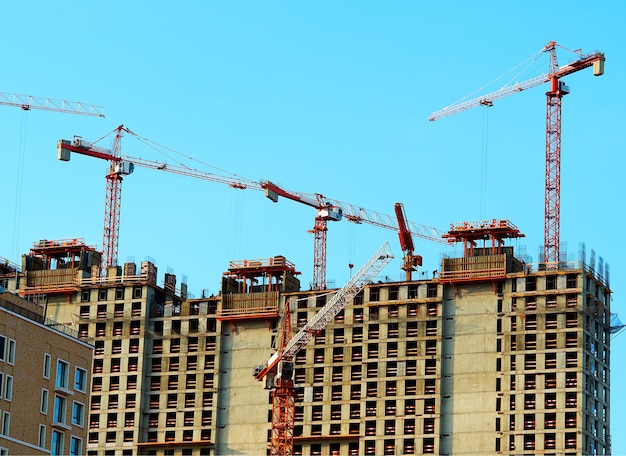 Multiple cranes constructing modern buildings background