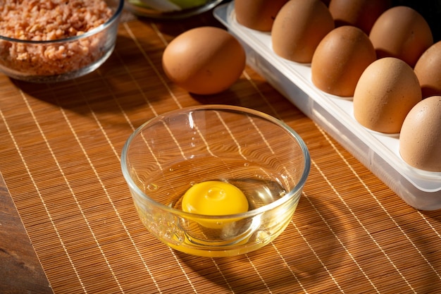 Multiple eggs and egg wash on wooden chopping board