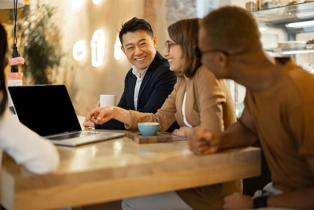 Multiracial business team watching something on laptop while working in cafe or restaurant