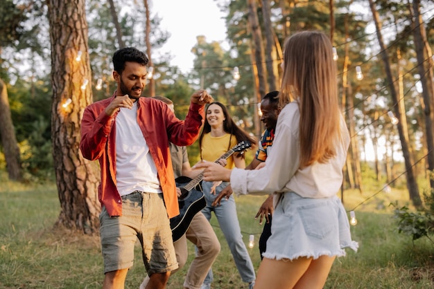 Multiracial couple dancing on the background of friends having fun