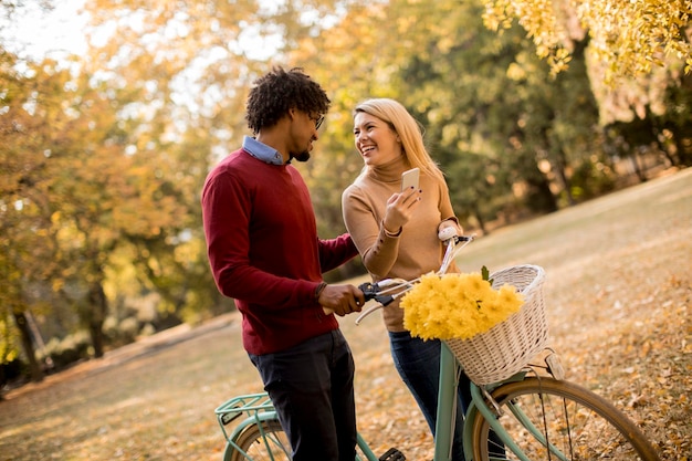 Multiracial couple with bicycle in the autumn park