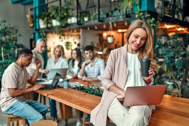 Multiracial creative people in modern office. Group of young business people and senior boss are working together with laptop, tablet, smart phone, notebook, graphs. Successful team in coworking