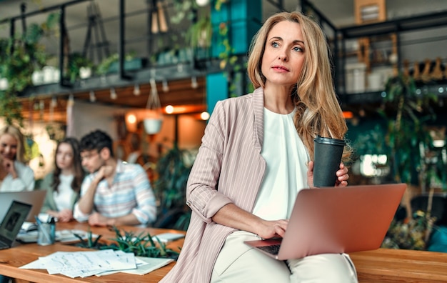 Multiracial creative people in modern office. Group of young business people and senior boss are working together with laptop, tablet, smart phone, notebook, graphs. Successful team in coworking