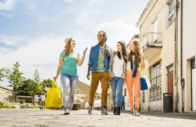 Multiracial friends group having fun together walking on town street