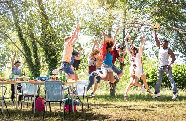 Multiracial friends jumping at barbecue pic nic garden party