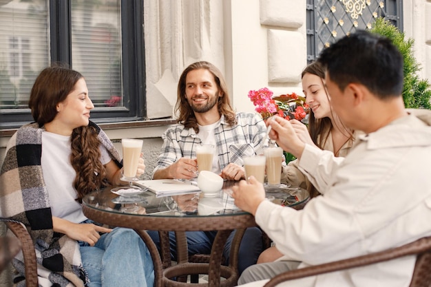 Multiracial group of friends having a coffee together in a cafe outdoors