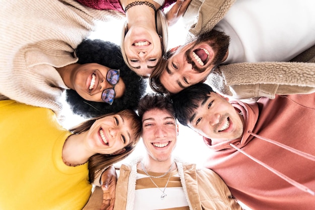 Multiracial group of friends standing in circle smiling at camera