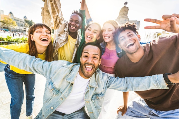 Multiracial group of people with arms up celebrating smiling at camera outside