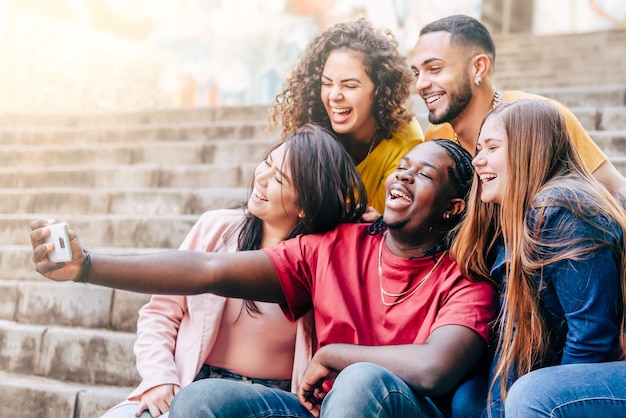 Multiracial group of young hipster friends make selfie with smartphone Happy life style concept with young students having fun together Focus on Black Man