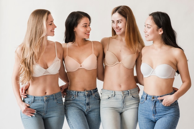 Multiracial group of young women wearing bras embracing and smiling