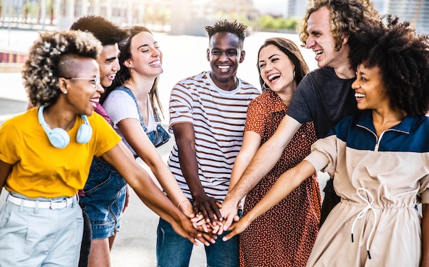 Multiracial happy young people putting their hands on top of each other