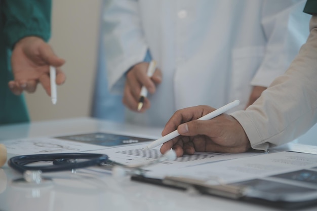 Multiracial medical team having a meeting with doctors in white lab coats and surgical scrubs seated at a table discussing a patients records