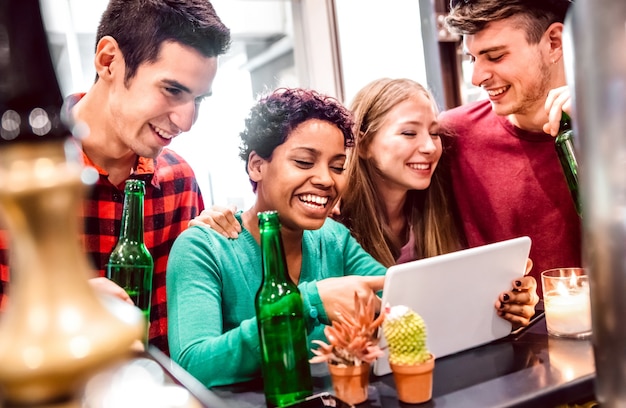 Multiracial milenial friends having fun with laptop at modern coworking space