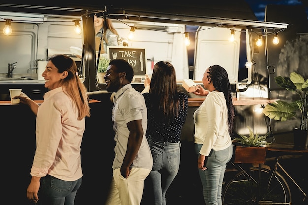 Multiracial people ordering food at counter in take away food truck outdoor - Focus on right african woman