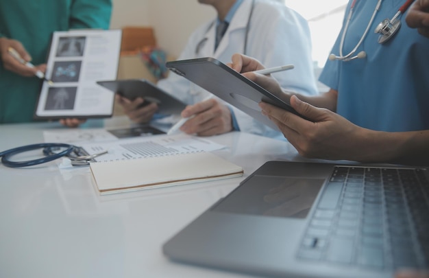 Multiracial team of doctors discussing a patient standing grouped in the foyer looking at a tablet computer close up view