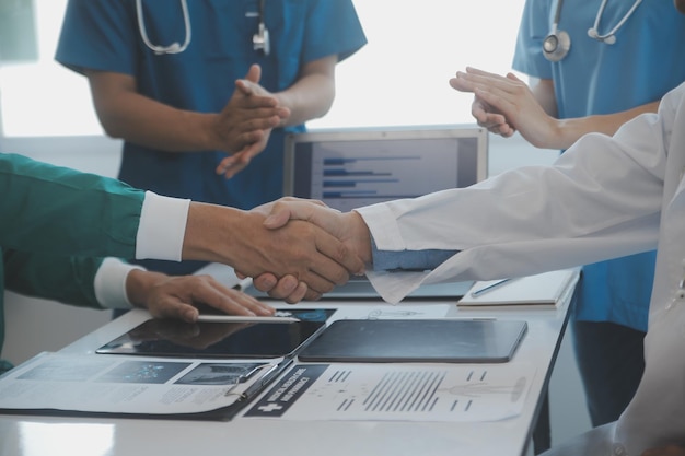 Multiracial team of doctors discussing a patient standing grouped in the foyer looking at a tablet computer close up view