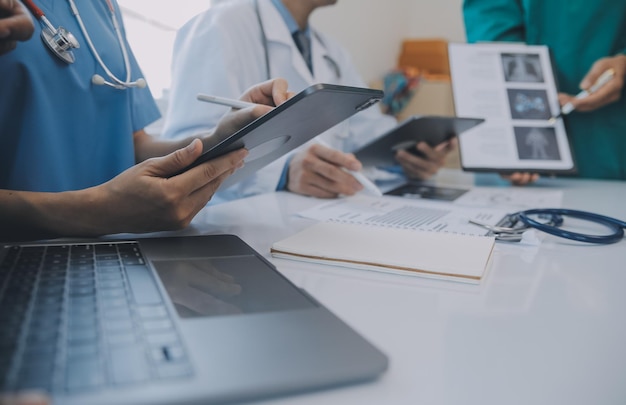 Multiracial team of doctors discussing a patient standing grouped in the foyer looking at a tablet computer close up view