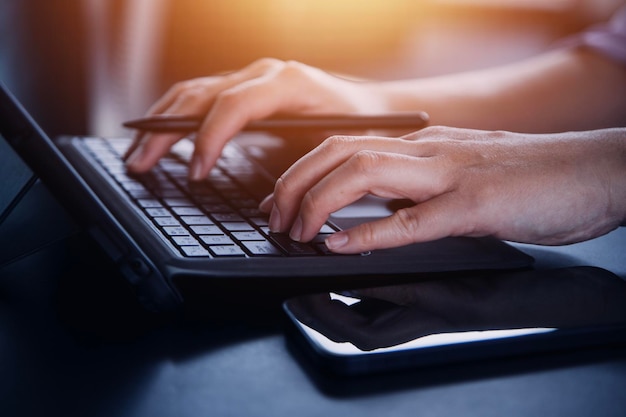 Multitasking businessman working in the office He is using touchpad while reading an email on laptop and taking notes on the paper