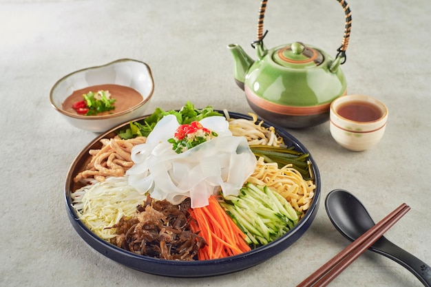 Mung Bean Flat Noodles tossed in Sesame Sauce served in a dish with chopsticks side view on grey background