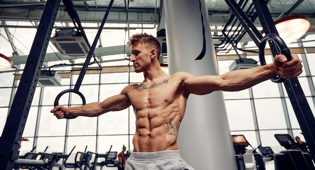 Muscleup exercise young man doing intense cross fit workout at the gym on gymnastic rings