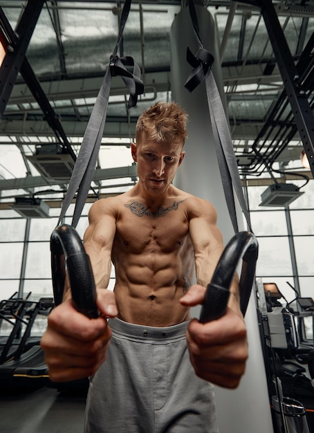 Muscleup exercise young man doing intense cross fit workout at the gym on gymnastic rings