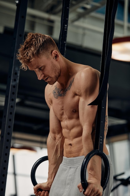 Muscleup exercise young man doing intense cross fit workout at the gym on gymnastic rings