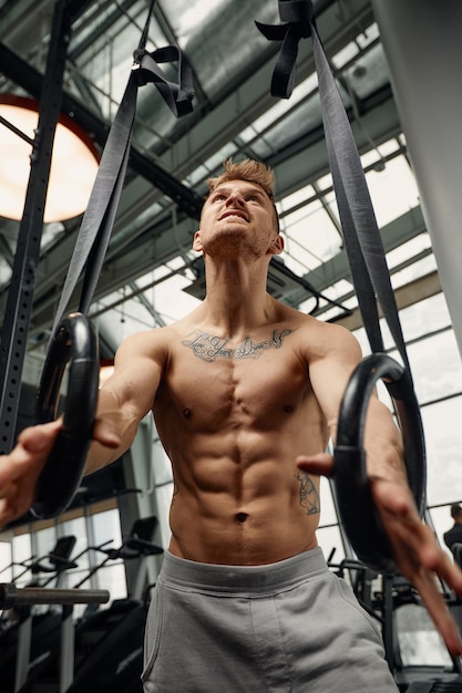 Muscleup exercise young man doing intense cross fit workout at the gym on gymnastic rings