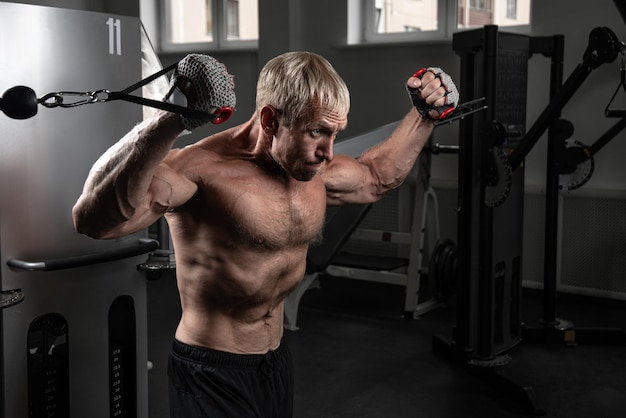 Muscular adult brutal man training on TRX loops in the gym Portrait of caucasian authentic bodybuilder doing exercises in HIIT workout