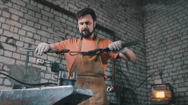 Photo muscular blacksmith in forge hammering steel products, small business