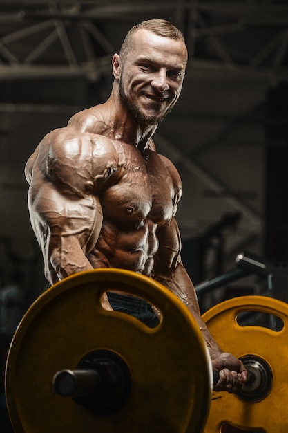 Muscular bodybuilder fitness man doing arms exercises in gym