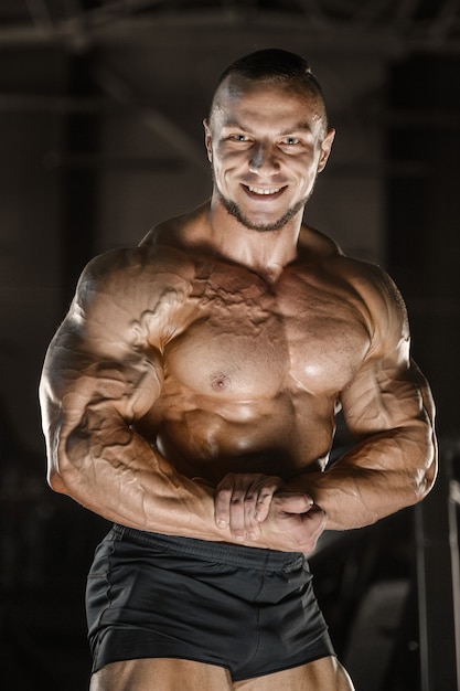 Muscular bodybuilder fitness man doing arms exercises in gym