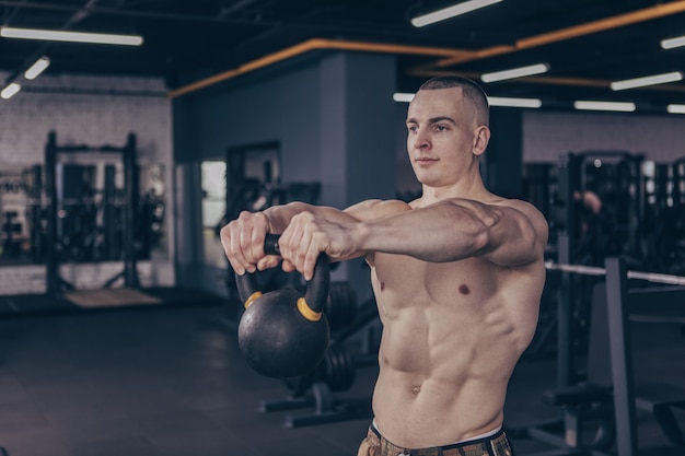 Muscular crossfit athlete working out with kettlebell