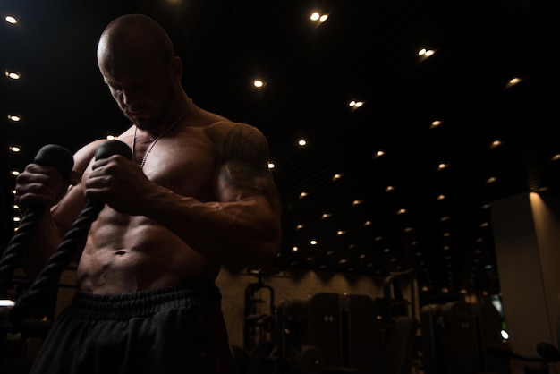 Muscular Fitness Bodybuilder Doing Heavy Weight Exercise For Biceps On Machine With Cable In The Gym