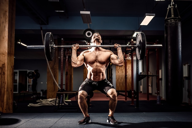 Muscular fitness man doing deadlift a barbell over his head in modern fitness center. Functional training.