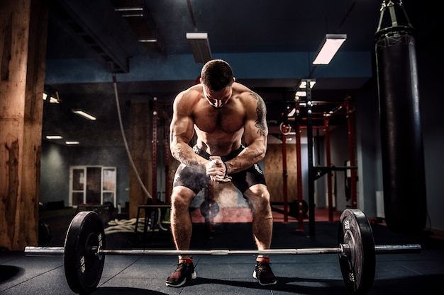 Muscular fitness man preparing to deadlift a barbell over his head in modern fitness center.Functional training.