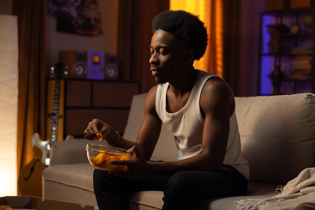 A muscular handsome man is spending an evening alone on the couch in the living room