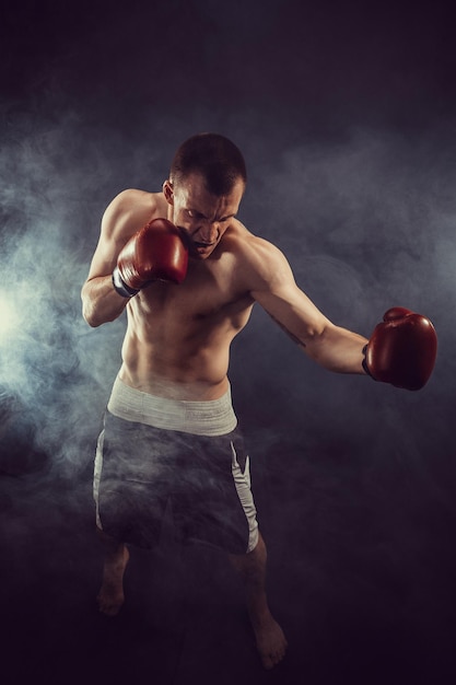 Muscular kickbox or muay thai fighter punching in smoke