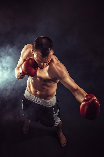 Muscular kickbox or muay thai fighter punching in smoke