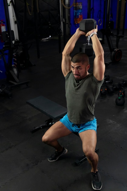 Muscular Latino man doing exercises for biceps sitting on a gym bench