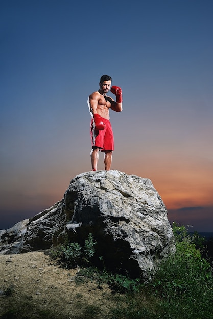 Muscular male boxer training outdoors