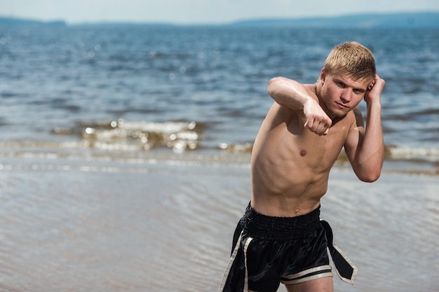 Muscular male fighter training. Boxer trains in the open air